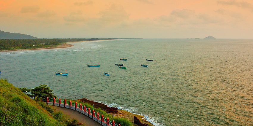 An aerial view of a scenic beach near Apsarakonda Waterfalls with golden sand and turquoise waters