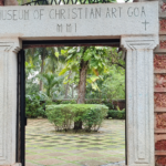 A stunning frontal view of a gate of a museum covered by greenery during the daytime.