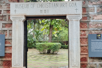 A stunning frontal view of a gate of a museum covered by greenery during the daytime.