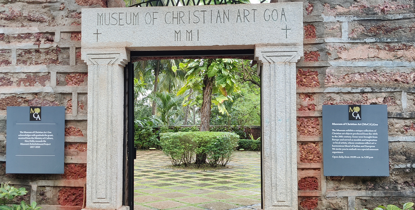 A stunning frontal view of a gate of a museum covered by greenery during the daytime.