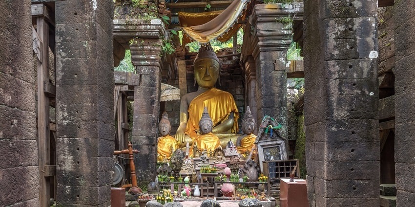 A picture of sculptures of Lord Buddha in an isolated area, covered with clothes and garlands