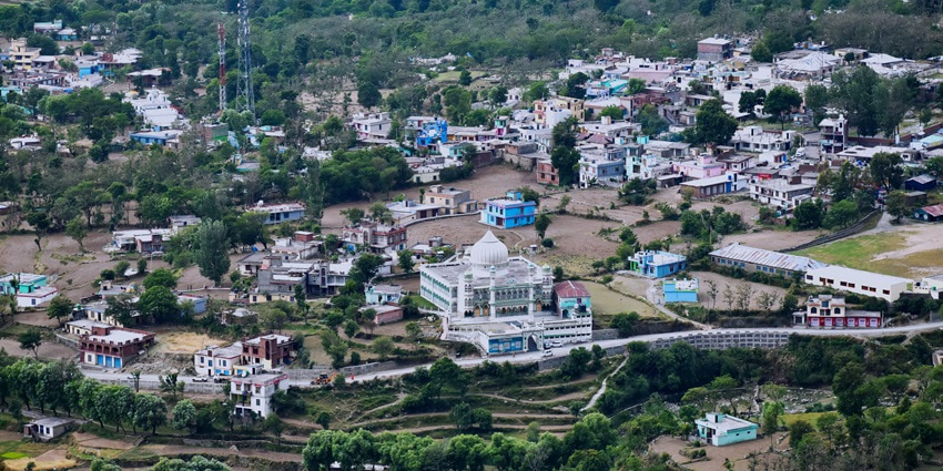 An aerial picture of a beautiful hill town with a cover of greenery and residential houses