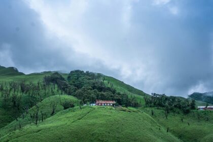 A stunning view of a lush green valley in Nagaland with a house on top during the day.