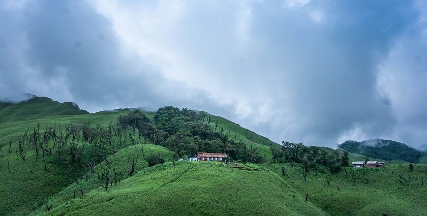 A stunning view of a lush green valley in Nagaland with a house on top during the day.