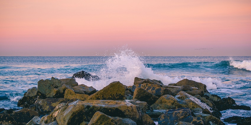 A scenic view of rhythmic waves hitting the majestic rocks at the Nai Harn Beach.