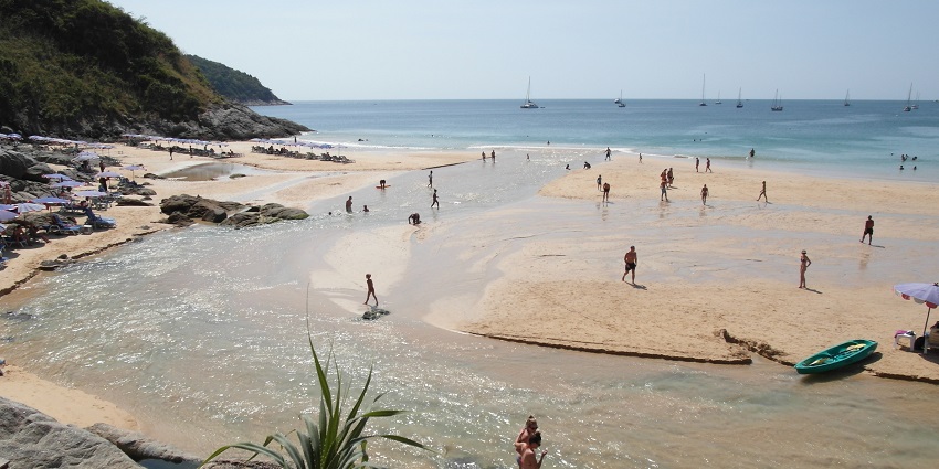 People leisurely spending their time at the beautiful Nai Harn Beach in Thailand.