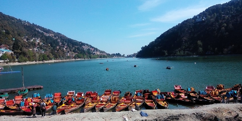 Serene view of Naini Lake in Nainital surrounded by hills and colorful buildings.