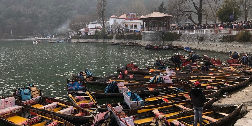 A picture taken from a corner of the Nainital Lake with boats parked and pleasant weather