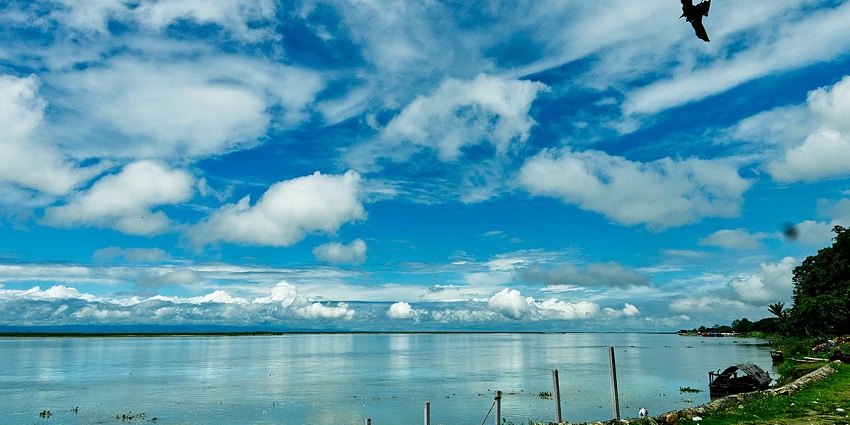 A breathtaking view of a sparkling azure lake in Assam surrounded by lush greenery.