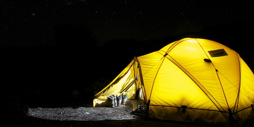 Breathtaking view of a yellow-lighted dome camp under a canopy of stars during the night.