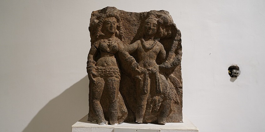 A picture of an ancient sculpture kept in a museum in front of a white wall