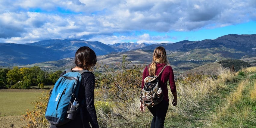 A glimpse of people walking through the rugged terrains surrounded by lush greenery.