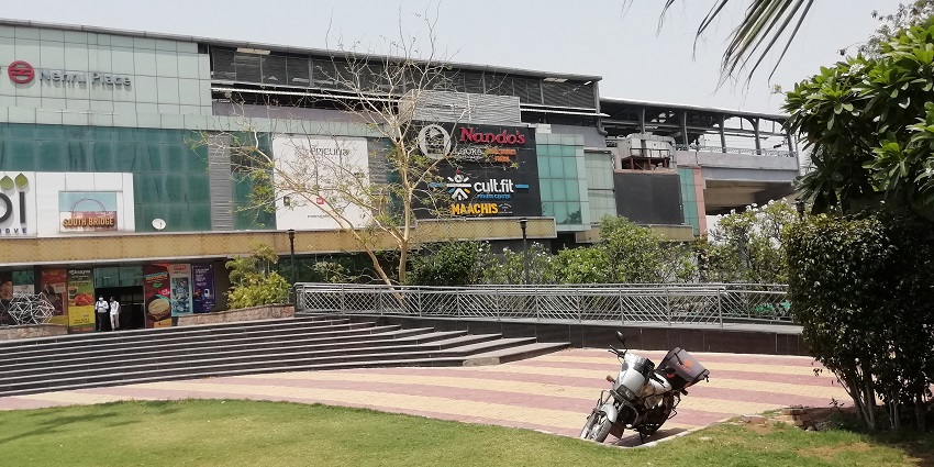A picture of Nehru Place Metro Station in New Delhi with a bike parked outside it.