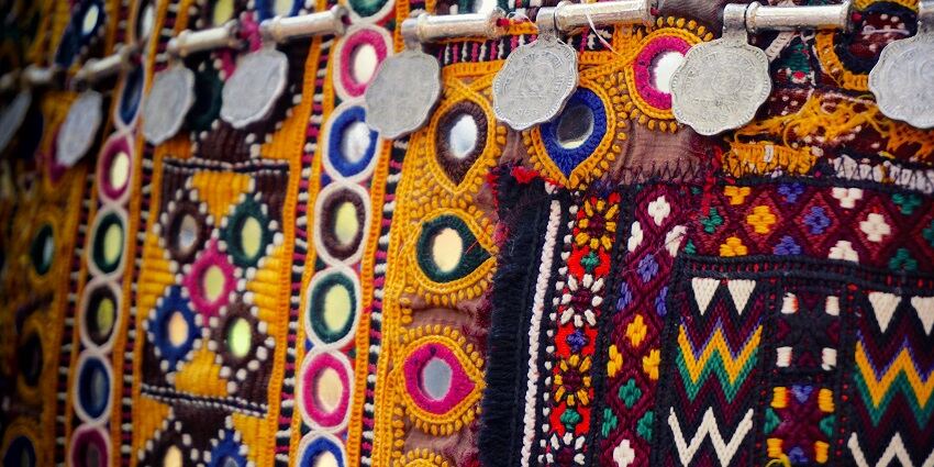 A stunning close-up view of a colourful textile displayed in front of shop during the day.