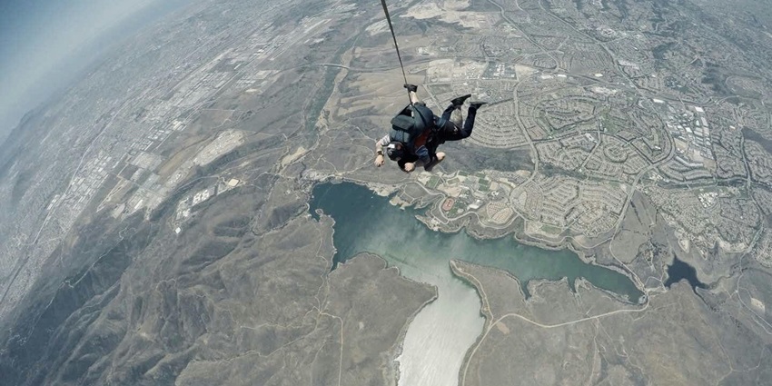 Skydiver in mid-air with a parachute deployed, showcasing the excitement of skydiving.