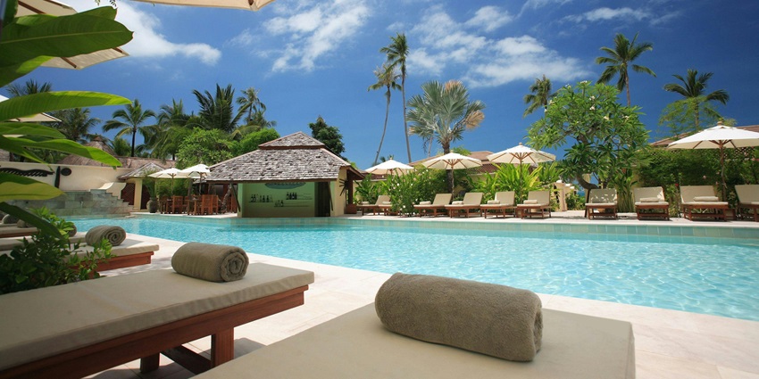 A picture of a resort with a swimming pool and tall pine trees in the premesis