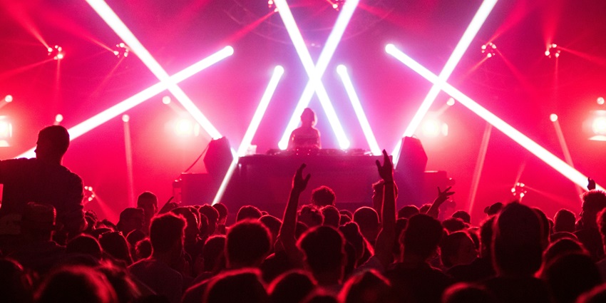 A view of a night club brimming with dazzling lights and people dancing on the floor.