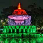 A breathtaking view of a colourful fountain in the middle of a park at nighttime.