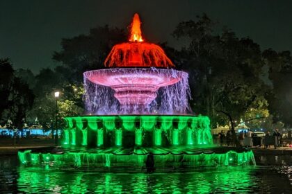 A breathtaking view of a colourful fountain in the middle of a park at nighttime.