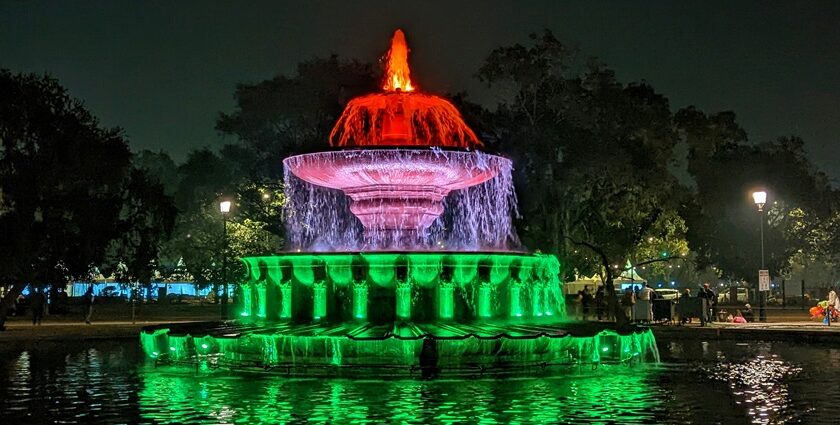 A breathtaking view of a colourful fountain in the middle of a park at nighttime.