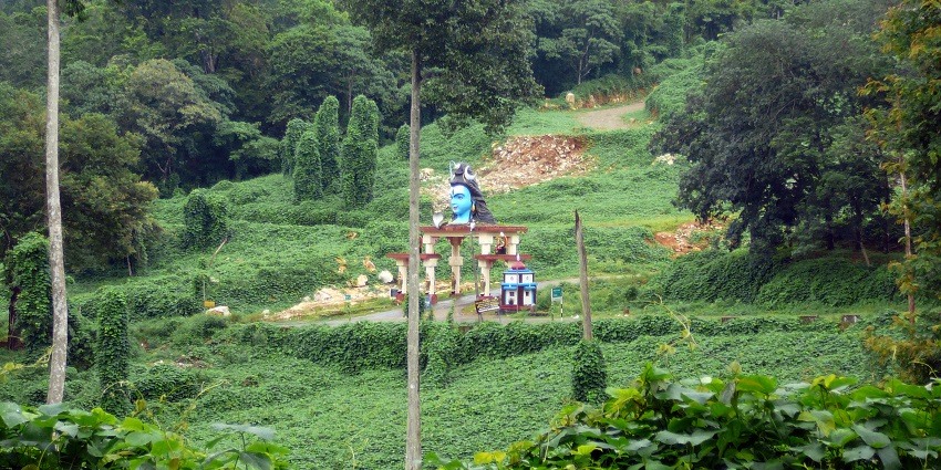 A breathtaking view of the Nilakkal Forest with a statue of Lord Shiva in front.