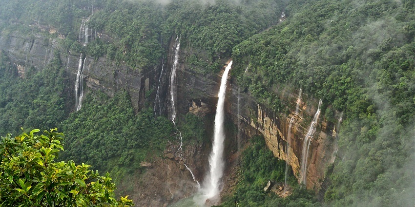 A picture of a big waterfall cascading from a hill into a pond of water