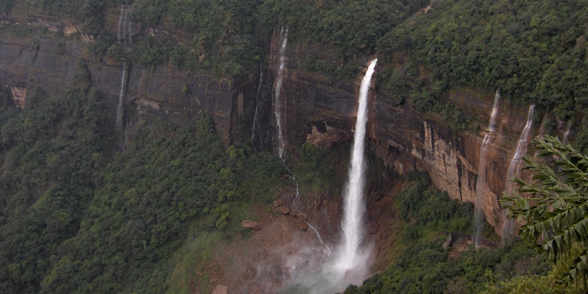 An aerial view of Nohkalikai Falls surrounded by lush greenery during the daytime.