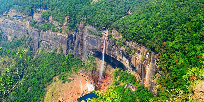 A breathtaking vista of cascading Nohkalikai Waterfalls surrounded by lush greenery.