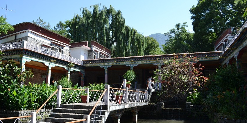 A picture of the Norbulingka Institute with lush green trees surrounding the building.