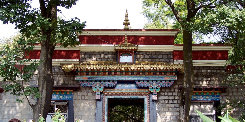 picture of an entrance of a traditional Tibetan style building surrounded by plants and trees