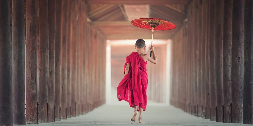 Novice Monk Walking Between Wooden Frame While Holding Umbrella - Phodong Monastery