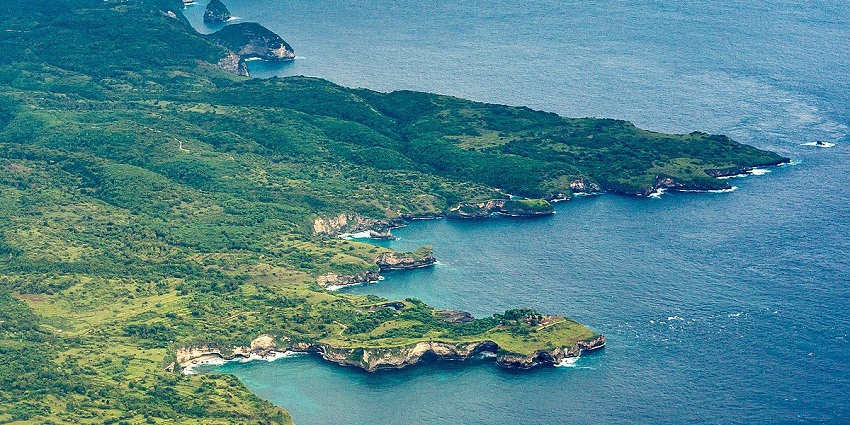 An aerial view of an Island in Bali with rocky and grassy terrains