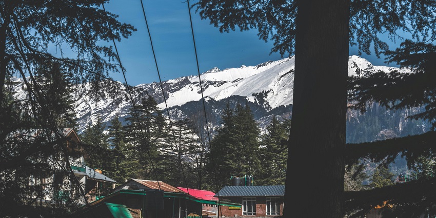 A mesmerising view of Old Manali with enormous snow-covered mountains in the background.
