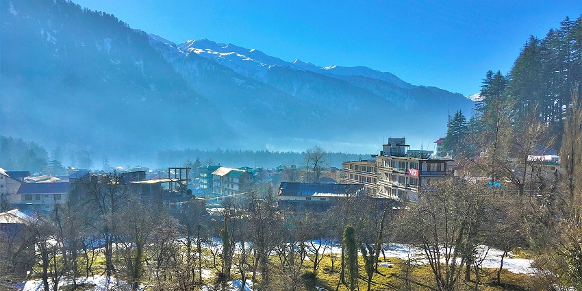 Scenic view of Old Manali with lush greenery and traditional wooden houses.
