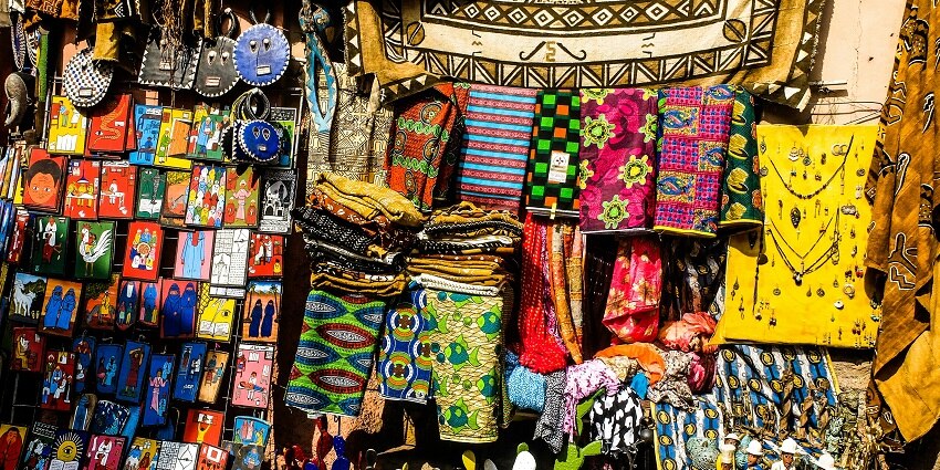 A stunning view of colourful clothes and accessories hanging in a shop during the day.