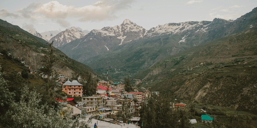 Image of picturesque old town nestled in mountains under a dramatic, cloudy sunset sky.