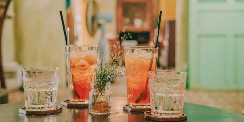 Four clear glass drinking cups with orange and clear liquids - explore at Terra Mayaa