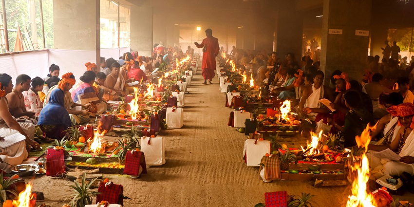 A picture from a temple hall with priests performing puja in front of a Havan Kund