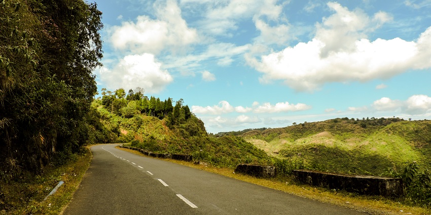 A picture of a road in Meghalaya near the Siju Caves with trees and greenery on both sides