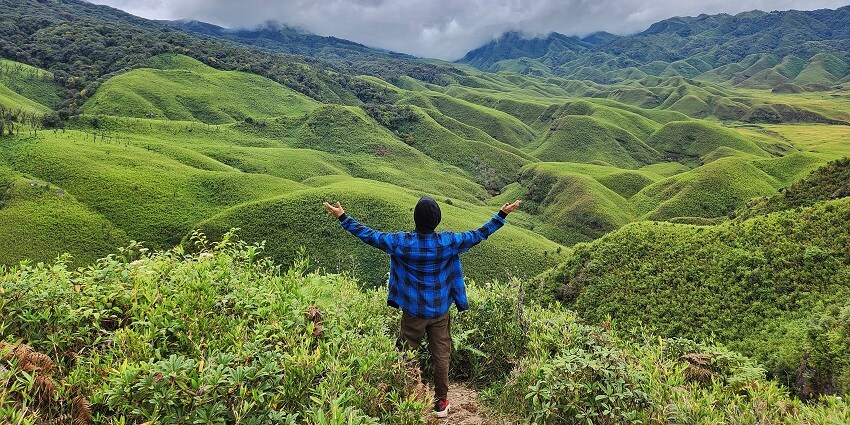 A picture of a person enjoying fresh air at a field in Nagaland with numerous hills