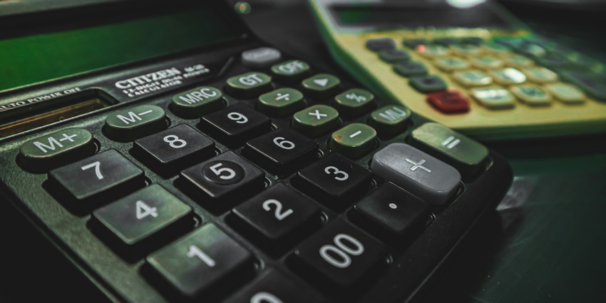 A selectively focused view of two black and white calculators sitting on a table.