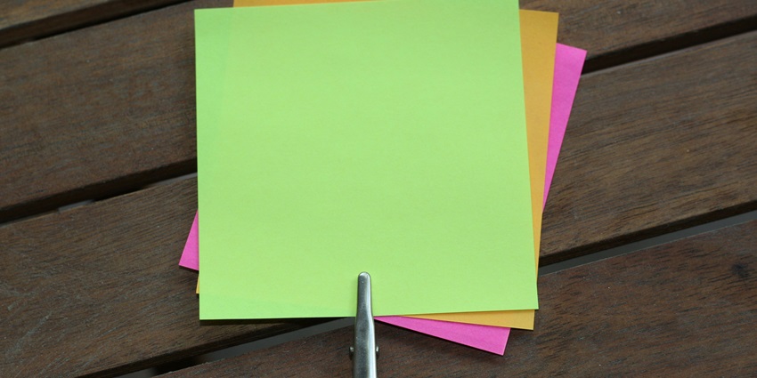 A focused view of colourful sticky notes such as green and yellow on a flat surface.