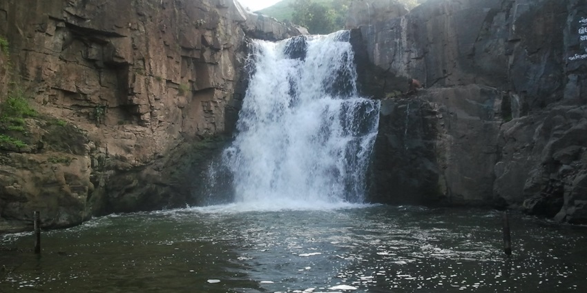 Water cascades over cliffs into a plunge pool amid forest similar to Kasaragod waterfalls