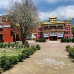 A stunning outer view of the monastery in Bir, Himachal Pradesh, that has a lush green garden.