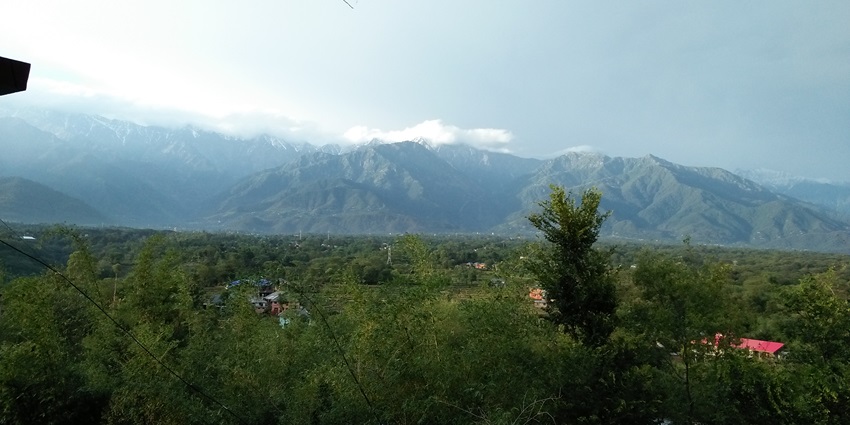 Dhauladhar Range in the background, featuring lush landscapes and stunning mountain vistas.