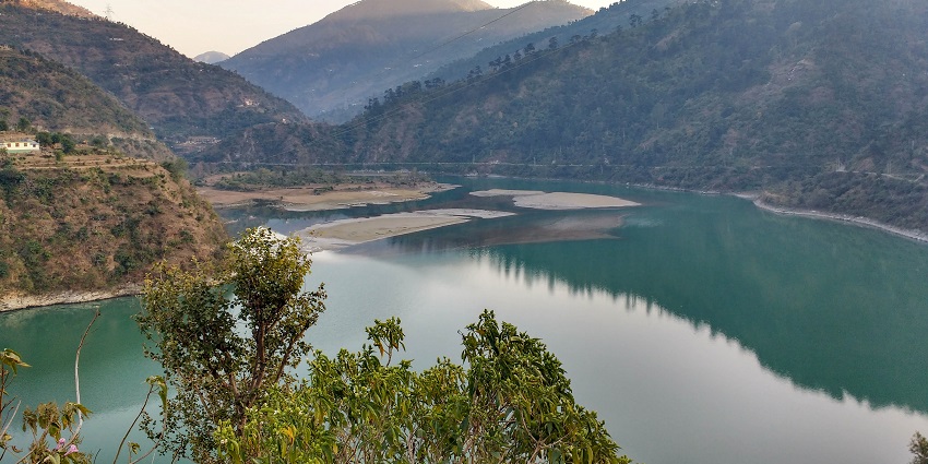 A picture of a dam in Kullu which is a must-visit as it features a lake amidst mountains