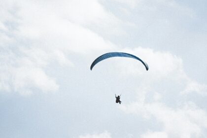 A mesmerising view of a person in the sky with a paragliding parachute during the daytime.