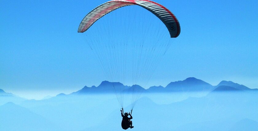 An image of a person enjoying the exciting sports activity above clouds in the daytime.