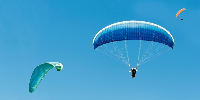 Enjoy paragliding activity as you soar through the azure skies while feeling the rush.