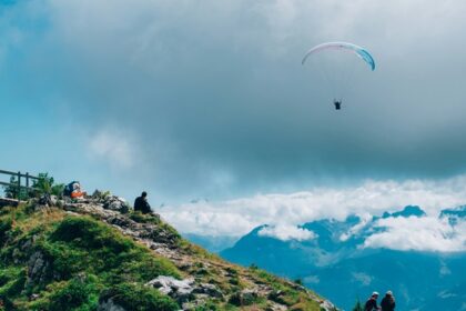 A breathtaking aerial view of a person enjoying Paragliding in the clear blue skies.